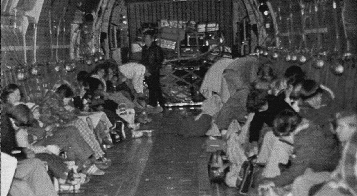 Evacuated families seated on the floor of a military cargo aircraft