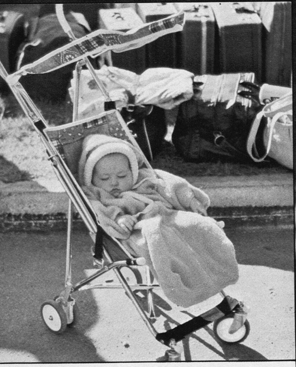 An infant asleep in a stroller beside a pile of luggage